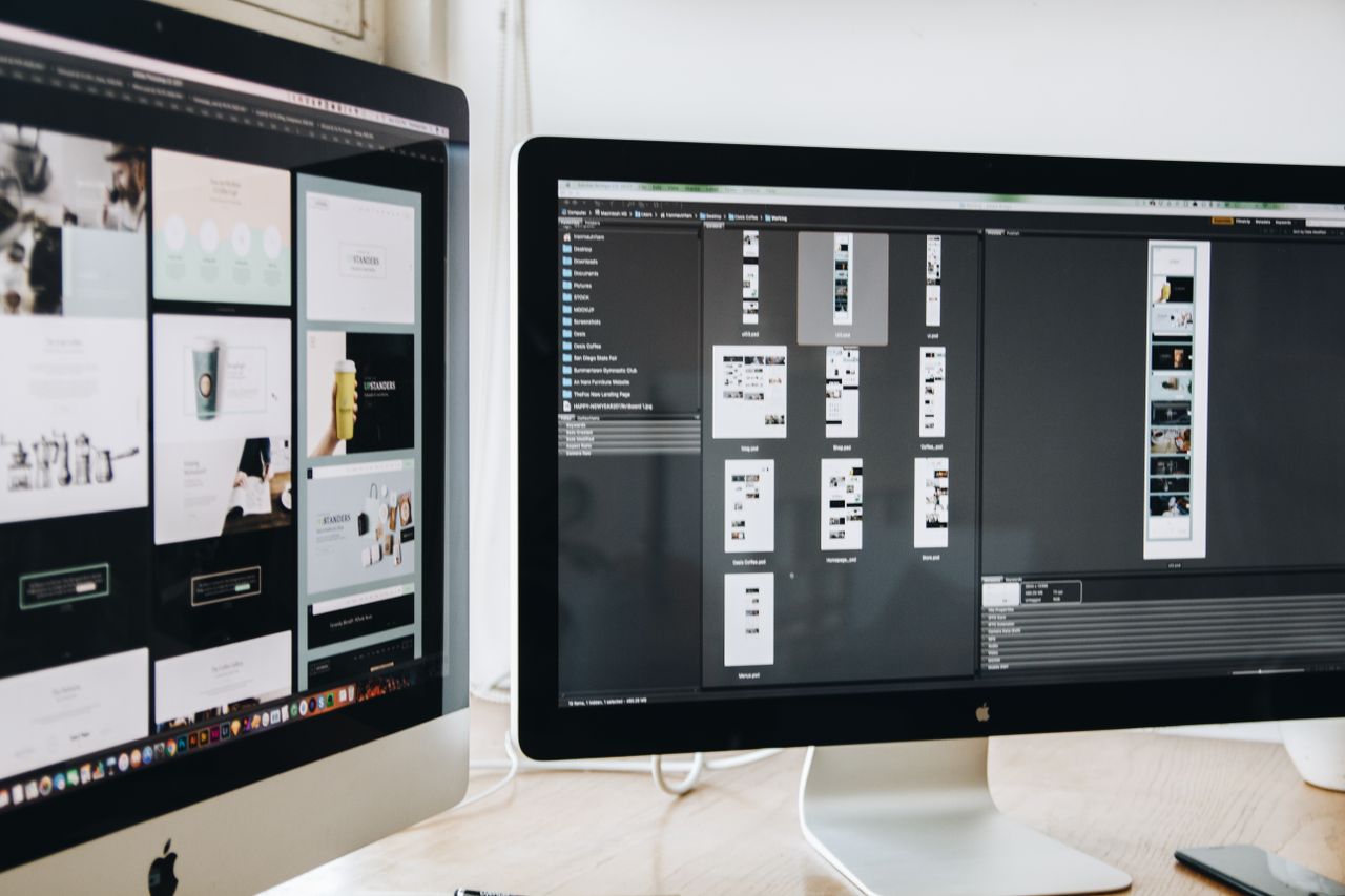 Un espace de travail moderne équipé de deux écrans d’ordinateur affichant des projets de conception web, mettant en avant la technologie et la productivité.